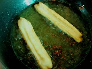 11、快手版无添加剂油条,锅里放入油烧热，放一点面试一下油温，下去的面周围冒小泡泡，好了可以开炸了，两手掐住两端，拉抻一下放入油锅