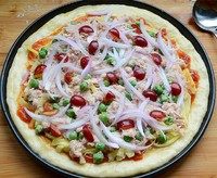 7、金枪鱼果蔬披萨,撒上三分之二已切成细条的马苏里拉芝士。再放上滤除油分的金枪鱼，用水焯过的控干的豌豆，稍稍烘烤过的洋葱和大樱桃。