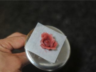 7、玫瑰花杏仁曲奇饼,油纸上放点豆沙，将油纸固定，用圆形花嘴在纸片的中间挤上花心，再用玫瑰花嘴沿着花心的边缘挤上三片玫瑰花片