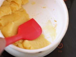 10、酥皮泡芙,混合后继续加热并不断用刮刀翻拌，当锅底上出现一层面团的薄膜(如图)，马上离火，把面团放到其他容器稍冷却。为能观察面团是否烫熟，这里换了一个搪瓷奶锅，如果使用不粘锅，就不容易分辨面团状态了。