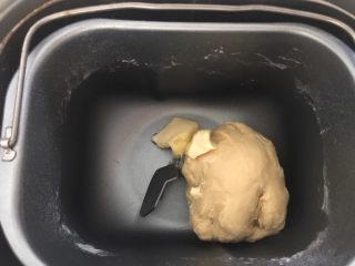 2、蓝莓夹心网纹面包,和面十分钟左右的时候面团就光滑了,这时候把黄油投入面包桶,继续和面