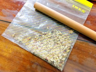 4、抹茶坚果一口酥,将其中的大粒果仁挑出来，放进干净的厚一点的保鲜袋，用擀面杖敲碎，尽量敲的碎一点，不然最后的成品会不太好看！