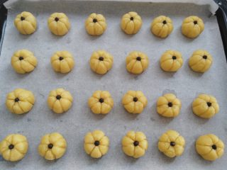 15、南瓜曲奇,把所有的饼干面团转移到烤盘上，饼干面团上放一颗耐烤巧克力或葡萄干