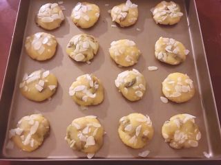 11、烘培之葡萄干杏仁酥,准备好烤盘,将每一个均匀沾上杏仁片放入烤盘中