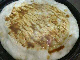 4、电饼铛披萨,面拿出来，揉一会排空气， 擀圆 放电饼档内， 叉点孔，防止鼓起来 盖子盖上一会后， 把做好的汤汁用勺子摊在上面