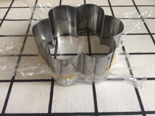 5、芒果慕斯,如果是无底的这种慕斯模具，就要用保鲜膜做底。保鲜膜堆叠成双层，盖住模具口，用皮筋绑住。再把保鲜膜中间拉平。