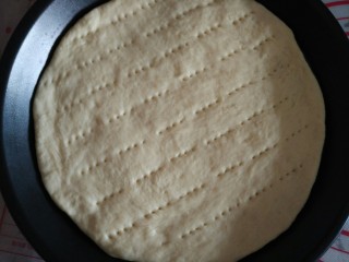 11、Pizza,醒发好的Pizza面团用擀面杖擀成圆形，放入Pizza盘（图中是9寸的Pizza盘），手工整好型，用叉子均匀刺孔