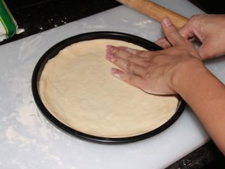 7、芝士榴莲披萨,铺上饼底，把圆边压厚，中间薄。☆记得用叉子在饼底砸多点气孔★。