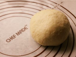 5、培根玉米粒披萨,放到揉面垫上进行排气。分割成两个面团。