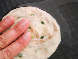 22、香葱千层饼,电饼铛预热后放入少许植物油(熟)，将图二十一中的面团放入电饼铛中，并用手按压成小面饼