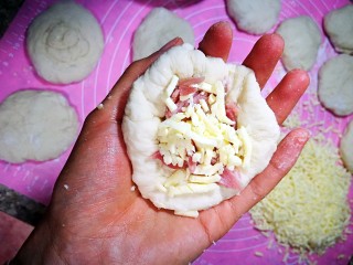 4、培根奶酪岩浆面包,面团松弛一刻钟，像包包子一样，先把每个面团擀成圆面皮，包入碎培根和马苏里拉奶酪碎，口要收好捏紧，否则容易露馅。包好，收口朝下，放到烤盘。