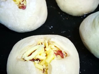 6、培根奶酪岩浆面包,每个面团十字口剪好后，为了烤时好看，把剪开的四个角往外拉拉，让口子更大，动作要轻，因为已经二次发酵完要烤了。