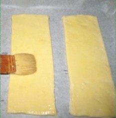 4、菠萝派,烤盘铺油纸，将铺垫在下方的面片摆在烤盘上，用叉子叉出均匀的小孔，表面抹一层蛋液。