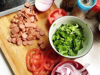 2、烤肠芹叶披萨,备上佐料，洋葱 切丝，芹菜叶略切，番茄切片，烤肠切片。