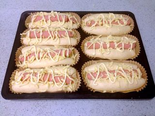 10、芝士肠仔包,烤箱预热180度。在发酵好的面包胚上挤上沙拉酱，撒上马苏里拉芝士碎。