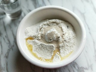 1、香甜玉米粒披萨,饼皮的全部食材加入容器中，(主料部分全部是饼皮食材)分次加入温水，因为不同的面粉吸水性不同。