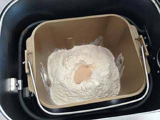 1、【芝心培根蘑菇披萨】,就是除了黄油外，按顺序把纯牛奶、全蛋液、盐、幼砂糖、高粉、干酵母粉全部倒入面包桶内，启动和面程序。