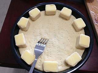 9、【芝心培根蘑菇披萨】,用叉子在面皮叉一些孔子。摆上芝心块。