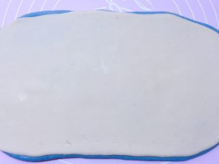 14、蓝天白云馒头,然后把蓝色面片翻过来，有白云的那面朝下放。再把擀好的白色面片叠到蓝色面片上，压实。