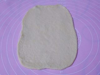 6、香葱芝士面包,取一个面团擀成长方形，松弛过的面团比较容易擀，觉得不太好擀的可以换一面再擀平，宽度不要太长，以超出火腿肠1-2厘米最合适