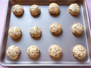 10、燕麦芝麻饼干,手上沾湿后，取一小块燕麦芝麻团搓成圆球状，摆放在不粘烤盘中，如果不是不粘烤盘，记得要垫油纸哦。