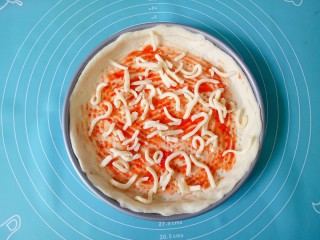 12、芒果披萨,在披萨皮上挤适量番茄酱涂抹均匀，撒上一层马苏里拉奶酪碎