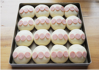 9、时下超级火爆的萌哒哒面包【面包超人挤挤面包】,表面刷上蛋液，将切成薄片的火腿肠铺在生胚上，每个生胚铺三片；