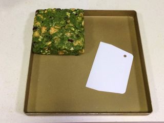 13、抹茶雪花酥,带上一次性手套慢慢推压紧实雪花酥团，然后进一步借用塑料刮板整形成方形。