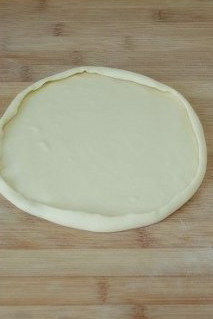 7、玄妙感觉的孜然羊肉披萨,将面团分成两个剂子，两次擀卷后醒10分钟，然后依次擀成圆形薄片，再将边缘卷起即成披萨饼底。