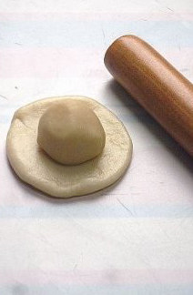 5、最接地气的鲜肉月饼,取一个水油皮剂子擀薄,上面放一个酥皮剂子,然后包起收口再按扁。