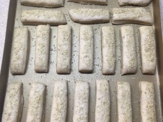 16、千层饼,表面喷上一层水。撒上白芝麻。放置温暖处发酵15分钟。