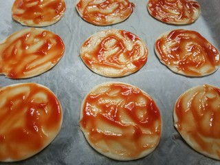 6、迷你披萨,用勺子将番茄酱抹匀