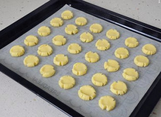 7、萌媚酥香的玛格丽特饼干,用拇指轻轻按压小面球，至其成饼状，边缘有开裂即可，也别按压的太薄，要稍有厚度才好。