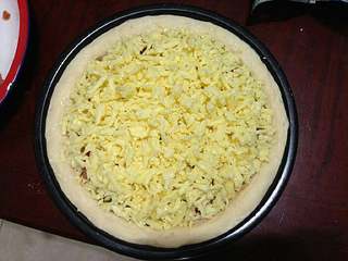 11、【培根菠萝披萨】,最上层撒满奶酪。（留少许菠萝、青椒、洋葱、培根，到最后烤好出盘做装饰。）