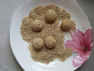 9、开口笑,小的面团上沾白芝麻后滚圆（小面团可以放在蘸有水的布上滚湿后沾上芝麻）。