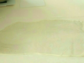 5、澎湖咸饼,将折叠过的面饼调转90度，让开口的部分冲左右两边，再把面饼擀开。