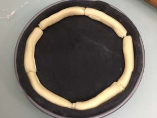 8、万圣节黑披萨,把面坯放入披萨烤盘里，把芝士卷放在面坯边