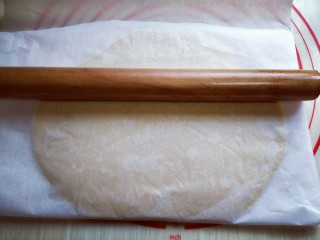 8、圣诞树饼干#预热圣诞节#,取一张油纸，把面团放上面，用擀面杖擀成约2mm厚圆饼。