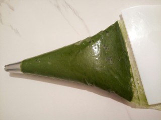 9、云朵抹茶曲奇,用的是8齿的裱花钉，裱花丁装入裱花袋，裱花袋前面剪一个小口，再把裱花袋套入一个杯子，装入面糊，装好以后，放在台板上，刮板把上面的全部刮下去