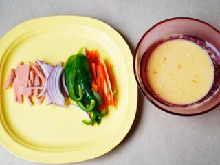 2、简易披萨蛋饼,鸡蛋打散加入面粉拌匀，火煺切成小条，青红椒，泮葱切成丝