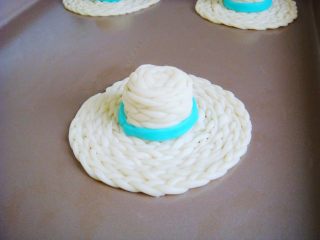 12、草帽编织饼干,取少许面团加入蓝莓粉揉均匀。（也可以选择自己喜欢的颜色）擀成薄片，切细条，围绕帽子一周粘贴好。除蓝色彩条外，均匀的刷上全蛋液。