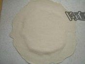 3、海鲜批萨,面团发酵完后, 在烤盘里均匀涂上少许油,将面团擀平放进烤盘(注意中间薄,边缘厚)