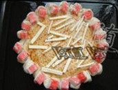 4、海鲜批萨,在面团边缘刷上油,后将边缘向内折起,按紧,用刀在边缘上切出口子来,放上切成块的蟹肉棒,