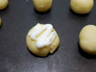 14、咸香芝士曲奇饼干,蛋黄酱装入裱花袋,或者用挤酱瓶,挤在芝士片上方即可。