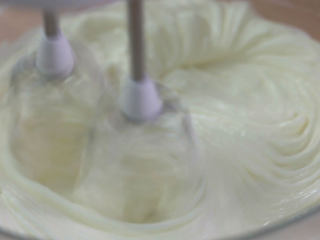 6、烤蓝莓重芝士蛋糕,然后细砂糖分三次加入芝士糊里面搅打,分三次是为了把芝士糊稍微打发一下,同时让细砂糖更容易的融化,不要打太发,否则后续会产生很多气泡以及烘烤的时候膨胀过度,细砂糖全部加进去之后,你会发现奶油芝士软了很多,这就表示细砂糖融化得差不多了,如果还看得见一点点,没关系,后续加入其它材料搅拌的时候它自然会融化了