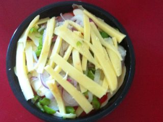 3、蛋Q虾仁小披萨,30分钟后将醒好的面拿出来，用手或擀面杖做成中间薄四周略厚的披萨面饼，在披萨磨具中涂层色拉油放入磨具中。随后依次刷上鲜辣酱、铺底层马苏里拉、摆鲜虾仁[此时可在鲜虾仁上淋一层蛋液]  洋葱丝和红绿彩椒交杂着覆盖虾仁上[同上再淋一层蛋液]   最后铺上最上层的马苏里拉，送入烤箱。如图