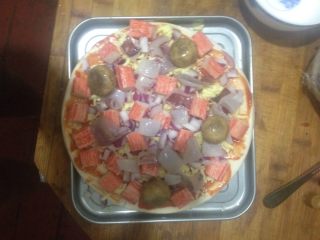 9、海鲜披萨,按照蟹肉棒的顺序,在放上鱿鱼。喜欢虾的可以放里面了。最后放的口蘑。因为老二喜欢口蘑。一个劲的说她要吃蘑菇????。(口蘑是前一天用鸡汤喂过。放在冰箱里准备给她炒肉吃的)最上面在均匀的撒上奶酪。要多放。边上也要放的