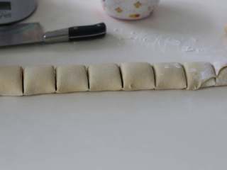 7、肉桂卷,卷成卷，捏紧收口，切掉两头不平整的面团，将面团切成9块。