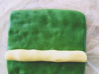 9、抹茶猕猴桃小饼干,原味面团搓成长约10cm长条，抹茶面团整形成宽10cm的面饼，如图面饼包裹上长条