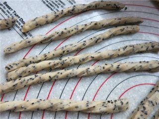 9、嘎嘣脆哒黑芝麻磨牙棒,将长条面团抻至合适长度向内搓几下形成波浪状